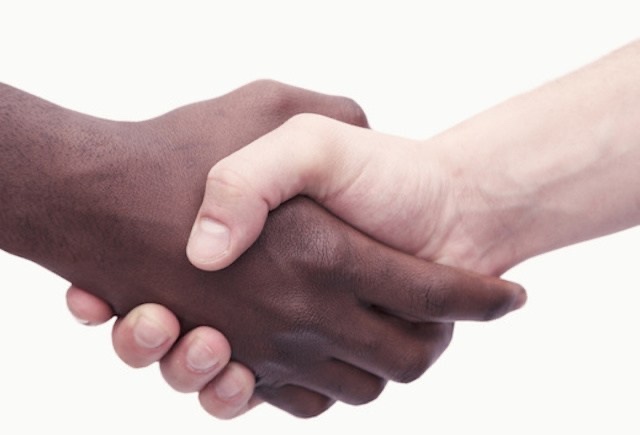 Two young men shaking hands, close-up, studio shot